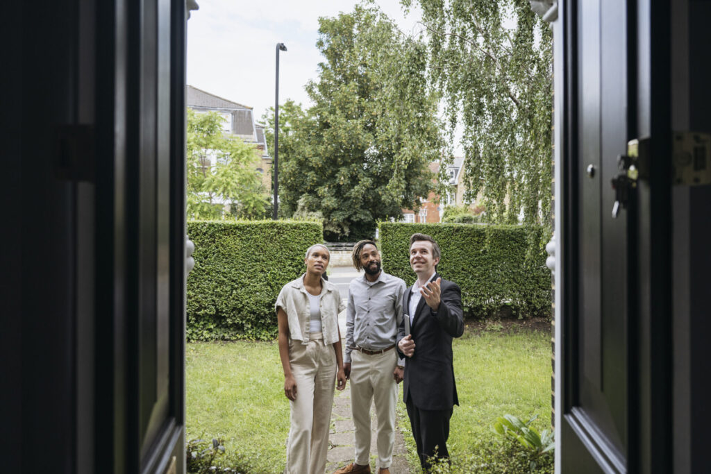 Real estate agent showing clients features of home exterior
